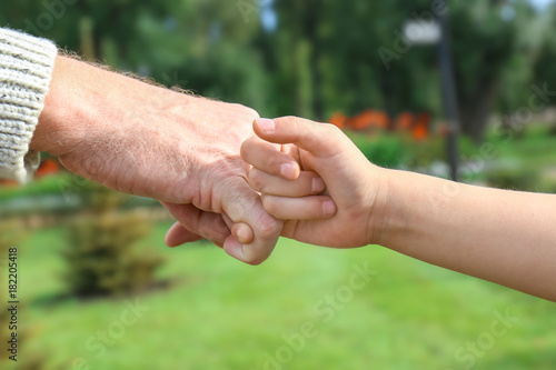 Senior man and his grandchild making pinky promise on blurred background © Africa Studio