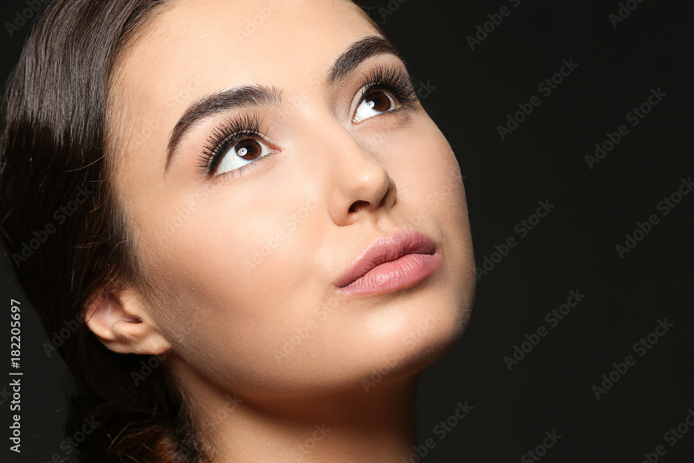 Beautiful young woman with eyelash extensions on dark background Beautiful young woman with eyelash extensions on dark background