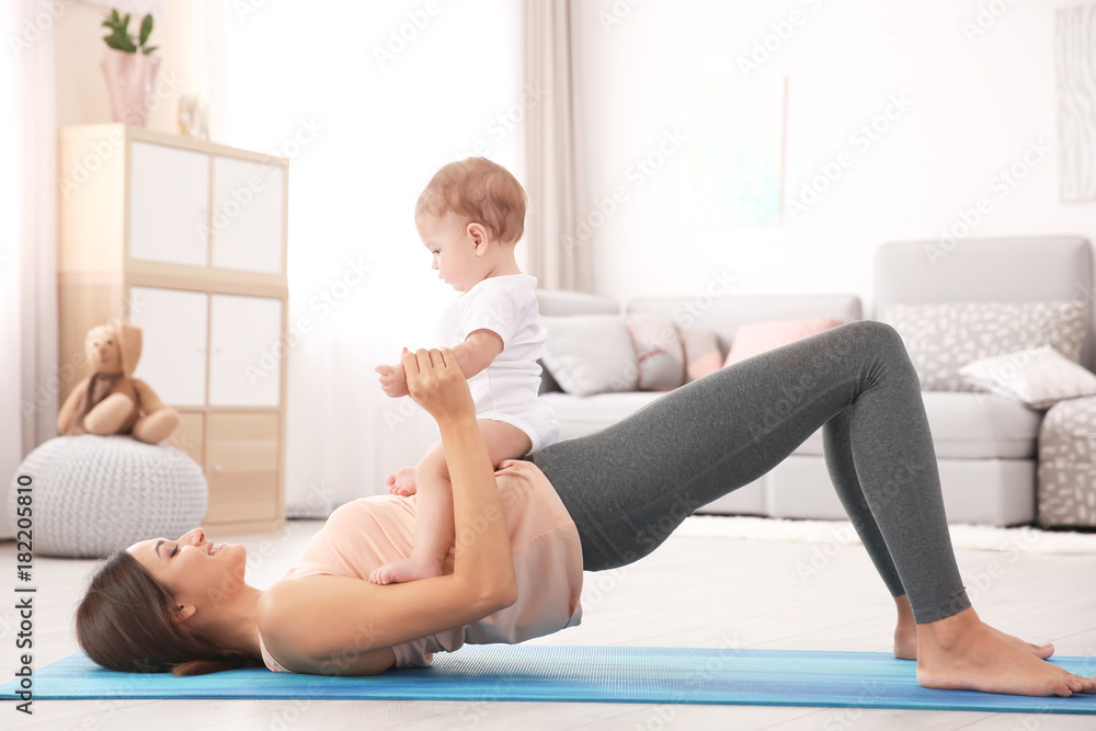 Fototapeta premium Young mother doing yoga with baby at home