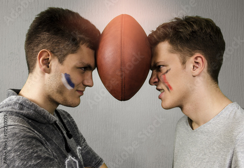 Fotomural Competitive brothers holding american football ball between their heads