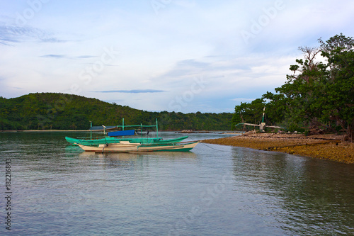 Traditional Pilipino boats moored in shallow waters of the sea lagoon in early morning. Tourist boats at the shore of Coron Island, Philippines.
