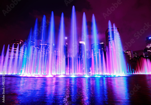 The colorful of fountain on the lake at night, near by Petronas Twin Towers and Suria Klcc shopping centre; with city on background. Kuala Lumpur, Malaysia.