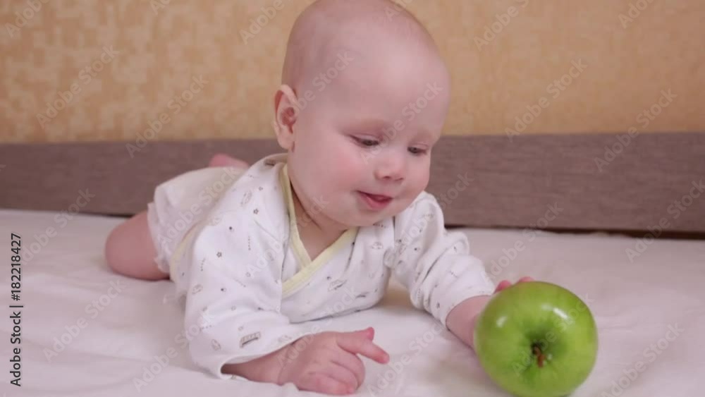 
a baby and an apple. portrait of adorable blue-eyed 6 months old baby boy. Natural light 
