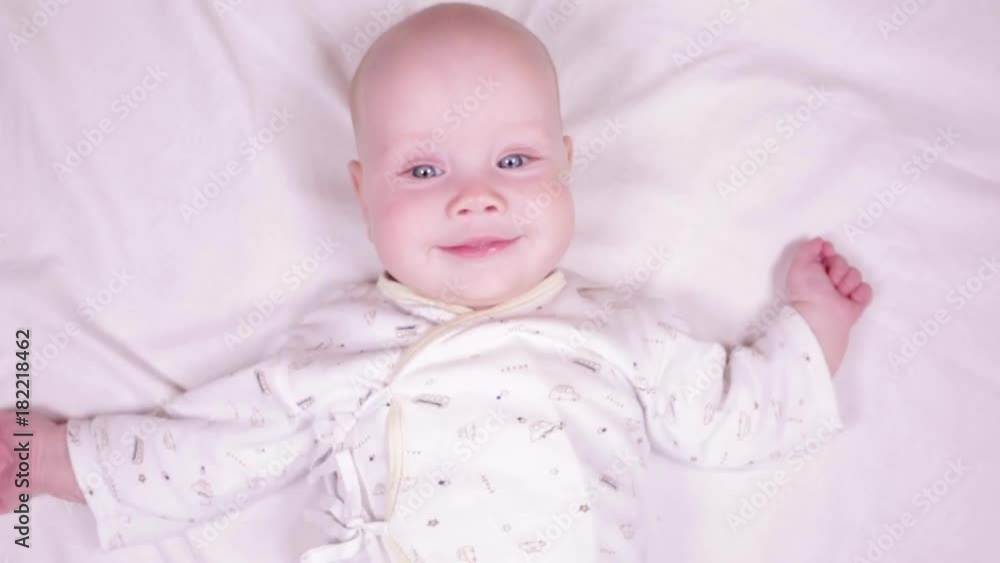 Slow motion portrait of adorable blue-eyed 6 months old baby boy smiling to someone behind the camera and showing his tongue Slow motion portrait of adorable blue-eyed 6 months old baby boy smiling to someone behind the camera and showing his tongue