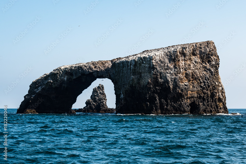 Naklejka premium Arch Rock natural bridge with a volcanic rock formation in the background at East Anacapa Island in Channel Islands National Park off the coast from Ventura, California.