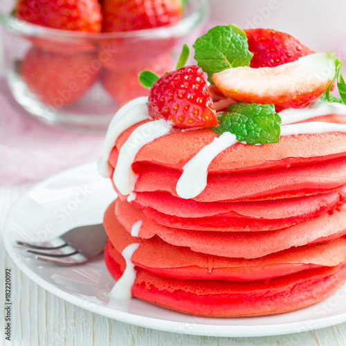 Stack of red velvet pancakes with yogurt and strawberry on white plate, square