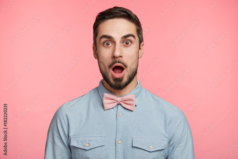 Handsome bearded surprised young male in formal festive clothes looks with bugged eyes and widely opened mouth, astonished to see huge cake prepared by friends, congratulate him with anniversary. Handsome bearded surprised young male in formal festive clothes looks with bugged eyes and widely opened mouth, astonished to see huge cake prepared by friends, congratulate him with anniversary.