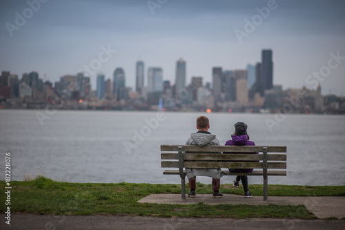 couple of people on the bench looking at the city
