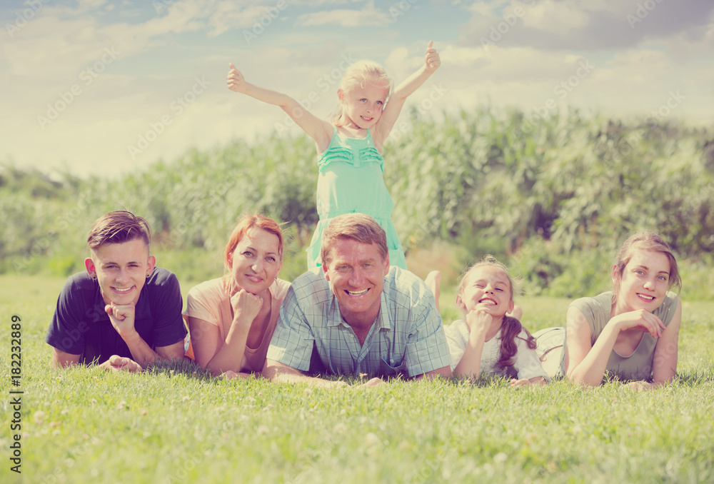 Portrait of smiling big family lying together on green lawn outdoors
