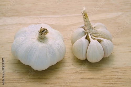 Whole garlic bulbs with and without outer shell on wooden table background. A type of cooking ingredient. Herbal plants and healthy food related to blood pressure, antibiotics, etc.