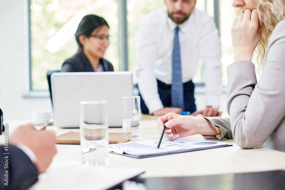 Group of talented financial managers discussing statistic data while having working meeting at spacious boardroom Group of talented financial managers discussing statistic data while having working meeting at spacious boardroom