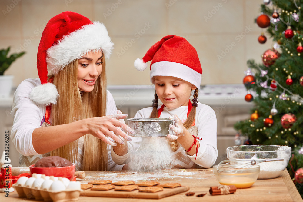 Happy mother and daughter playing with cookie flour at kitchen table while making Christmas cookies. Happy mother and daughter playing with cookie flour at kitchen table while making Christmas cookies.
