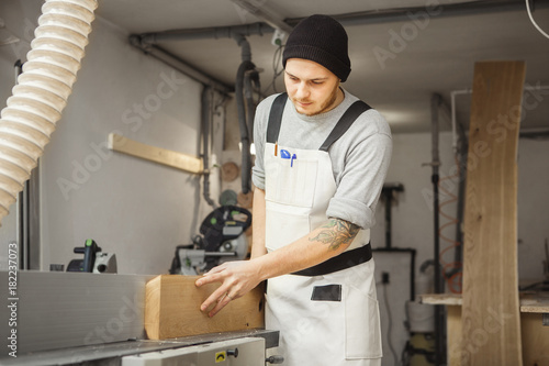 Worker processes board on woodworking machine