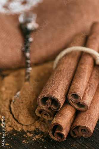 Cinnamon sticks and powder on rustic wooden Board closeup. Spices. Seasonings. Selective focus