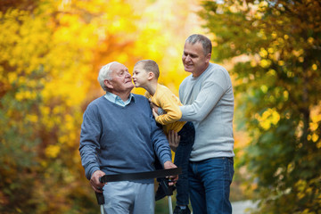 Elderly father adult son and grandson out for a walk in the park.