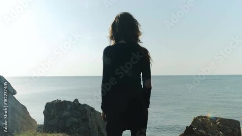 Young woman's silhouette at collapsed fort ruins on a rock cliff in Liepaja