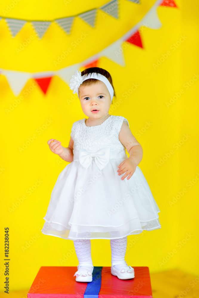 beautiful little girl in white dress is standing on big gift box. beautiful little girl in white dress is standing on big gift box.
