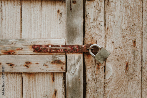 Ancient wooden closed door detail with a padlock. © daviles