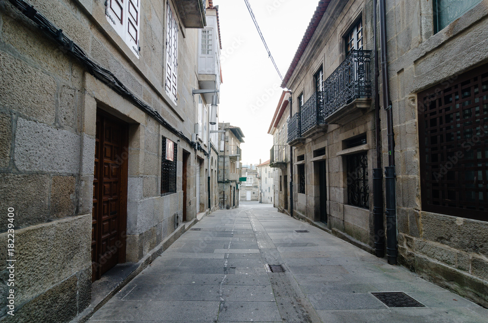 Empty street in town's historic quarter Pontevedra (Spain). Masonry walls steel gratings in the windos and wood door. Horizontal.