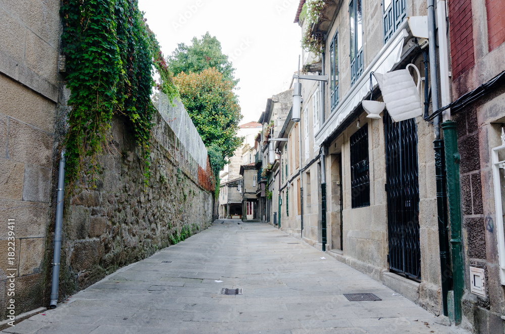 Empty street in town's historic quarter Pontevedra (Spain). Masonry walls steel gratings in door and coffee cup symbol in a coffee shop Empty street in town's historic quarter Pontevedra (Spain). Masonry walls steel gratings in door and coffee cup symbol in a coffee shop