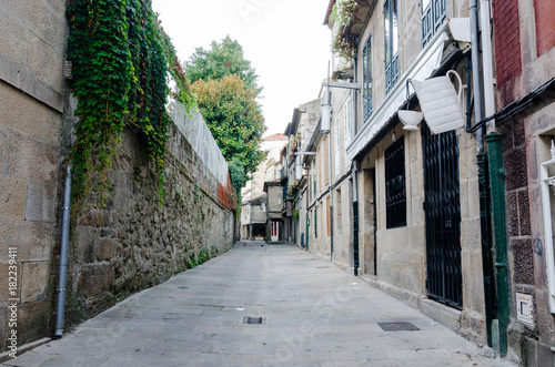 Empty street in town's historic quarter Pontevedra (Spain). Masonry walls steel gratings in door and coffee cup symbol in a coffee shop