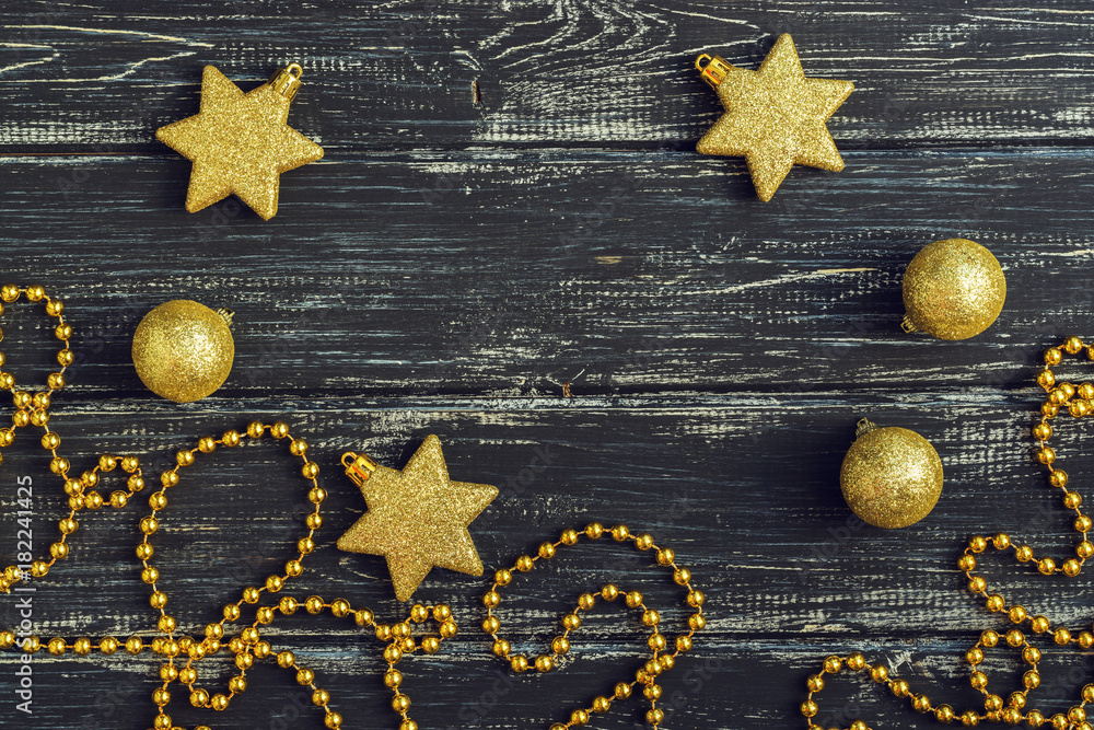 Gold stars and Christmas balls on a black wooden background. - obrazy, fototapety, plakaty 
