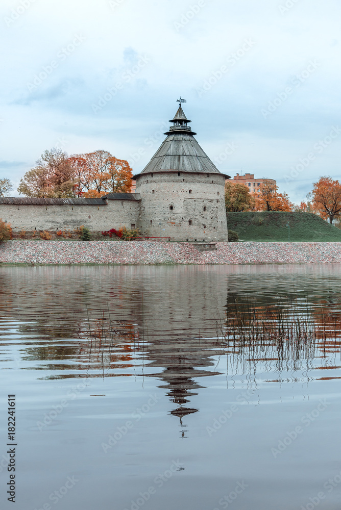 Pokrovskaya tower and fortress wall reflecting in the river. Autumn landscape of Pskov.