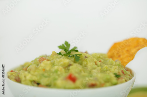 Avocado dip guacamole with tortilla chips in a white bowl 