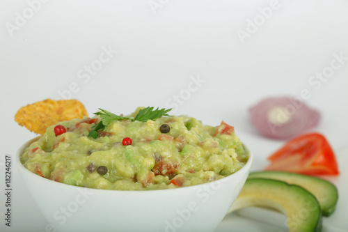 Traditional latinamerican mexican avocado sauce guacamole with tortilla chips in white bowl