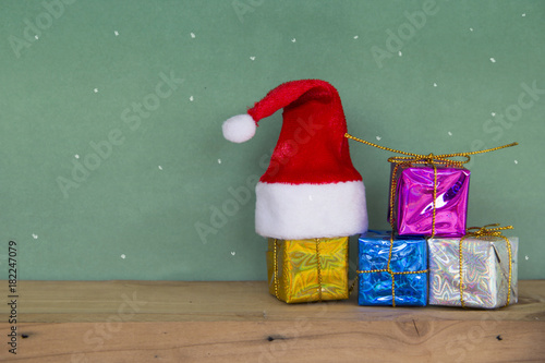 Merry christmas Happy new year. Red Santa hat with colorful gift box on wooden floorand and scene green board background space leave blank for writing greetings and Have Snow  written with chalk. photo