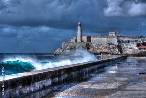 Cuba, Havana. Waves Breaking on the Malecon Sea Front. El Morro Fort in Background
