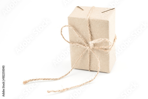Vintage brown craft paper gift box tied with brown rope bow ribbon isolated on white background for Christmas, New Year and Valentine Day present.