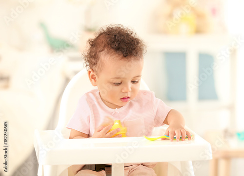 Cute baby with spoon sittin...