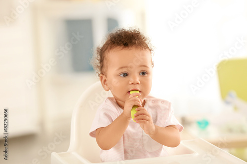 Cute baby with spoon sitting in room