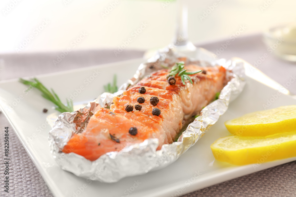 Plate with tasty grilled salmon and lemon slices on table, closeup Plate with tasty grilled salmon and lemon slices on table, closeup