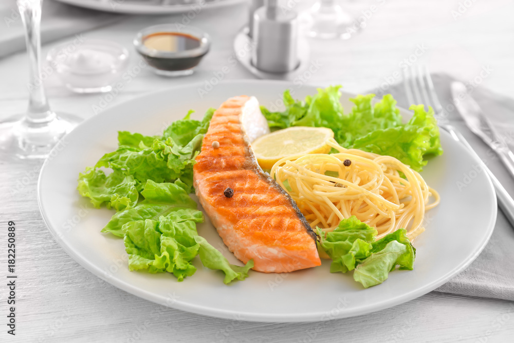 Plate with tasty grilled salmon and pasta on table Plate with tasty grilled salmon and pasta on table