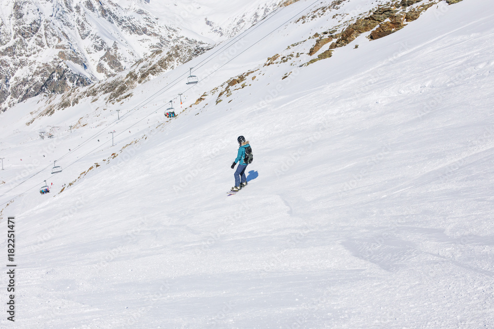 Girl snowboarder on the background of mountains in the winter season.