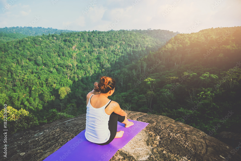 Naklejka premium Asian women relax in the holiday. Play if yoga. On the Moutain rock cliff. Nature of mountain forests in Thailand