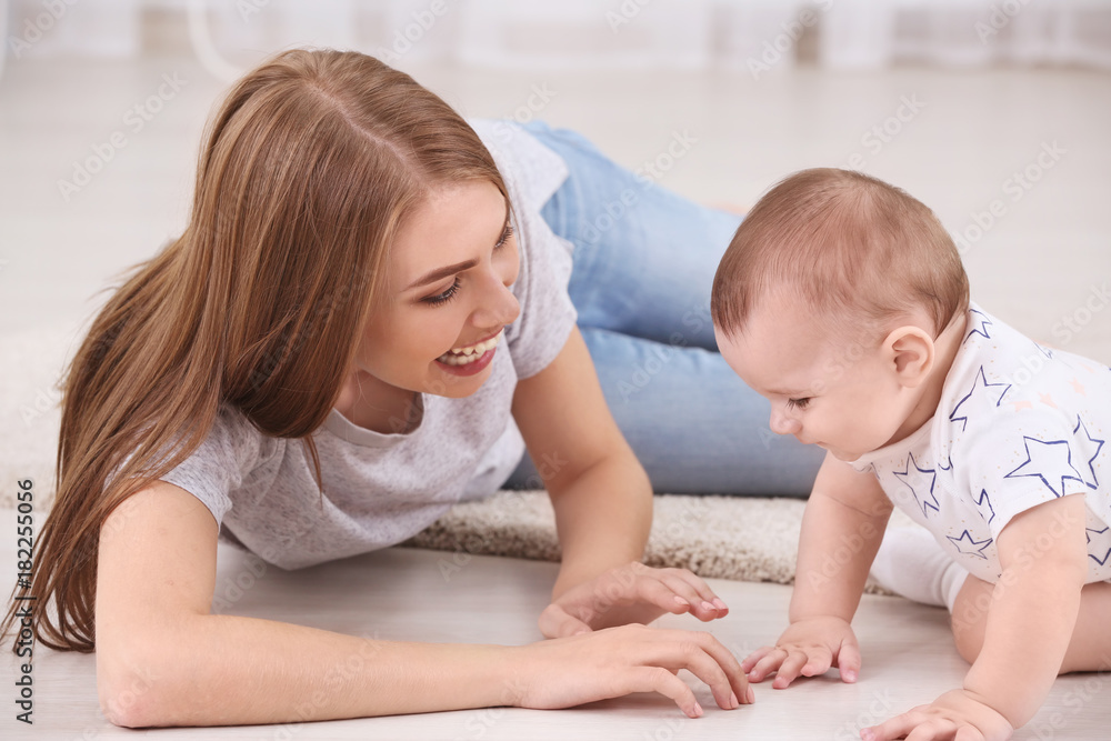 Young mother and cute baby playing on floor at home Young mother and cute baby playing on floor at home