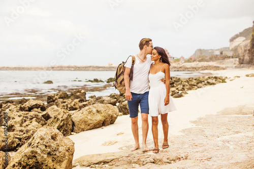 multiracial couple kissing on a beach