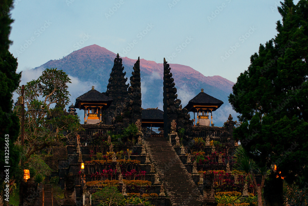 Balinese sacred mountain Agung colored in pink by sunset light. Main Bali temple Pura Besakih at the foot of the volcano Agung.