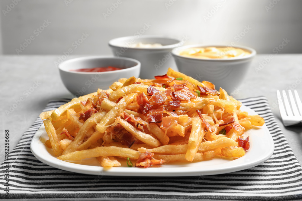 Fototapeta premium Plate with french fries and bacon on table