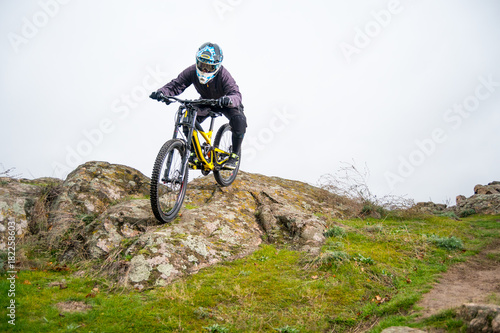 Professional Cyclist Riding Mountain Bike Down the Rocky Hill. Extreme Sport and Enduro Biking Concept.