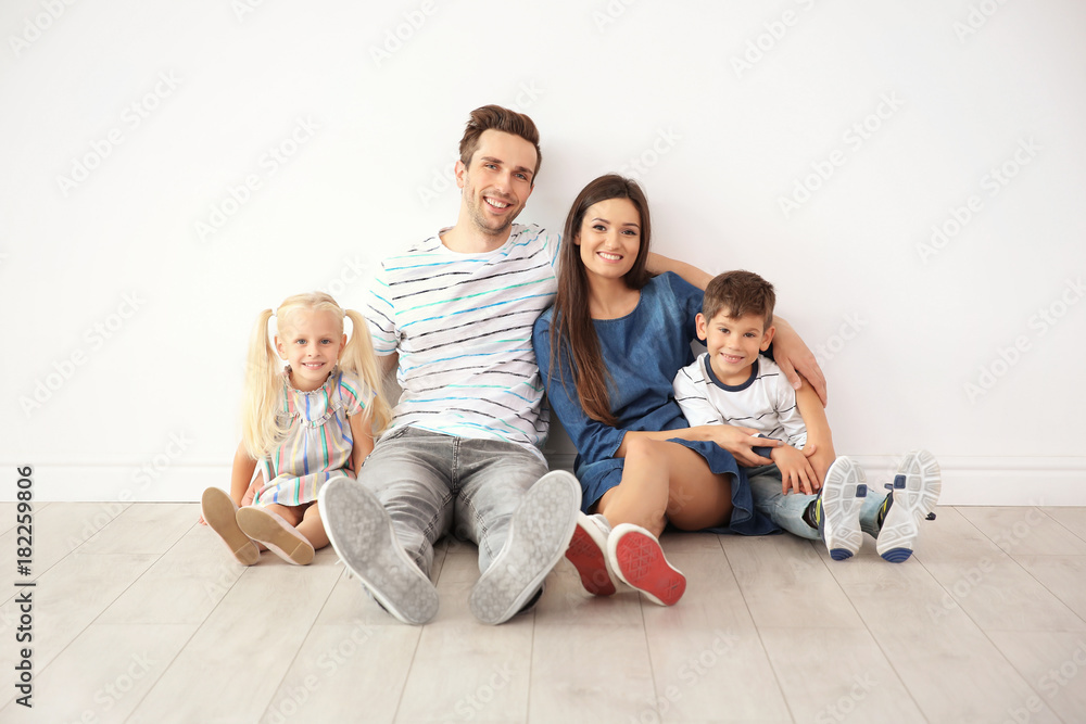 Happy family sitting near wall in their new home Happy family sitting near wall in their new home