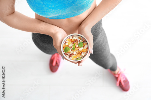 Young woman holding bowl with oatmeal in hands