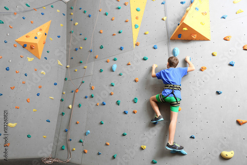 Young boy climbing wall in gym