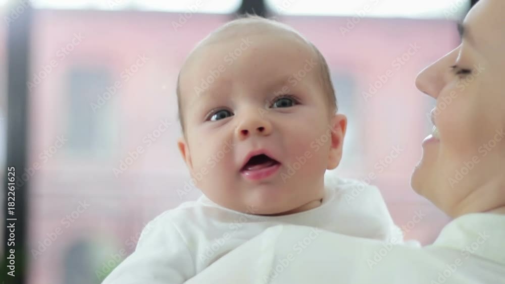Portrait of a cute newborn baby smiling in her mother arms, close up Portrait of a cute newborn baby smiling in her mother arms, close up