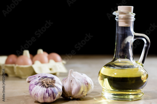 Garlic, eggs and oil on a wooden kitchen table. Kitchen with products for food preparation.