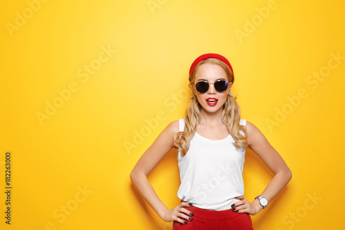 Attractive hipster girl with sunglasses on color background © Africa Studio