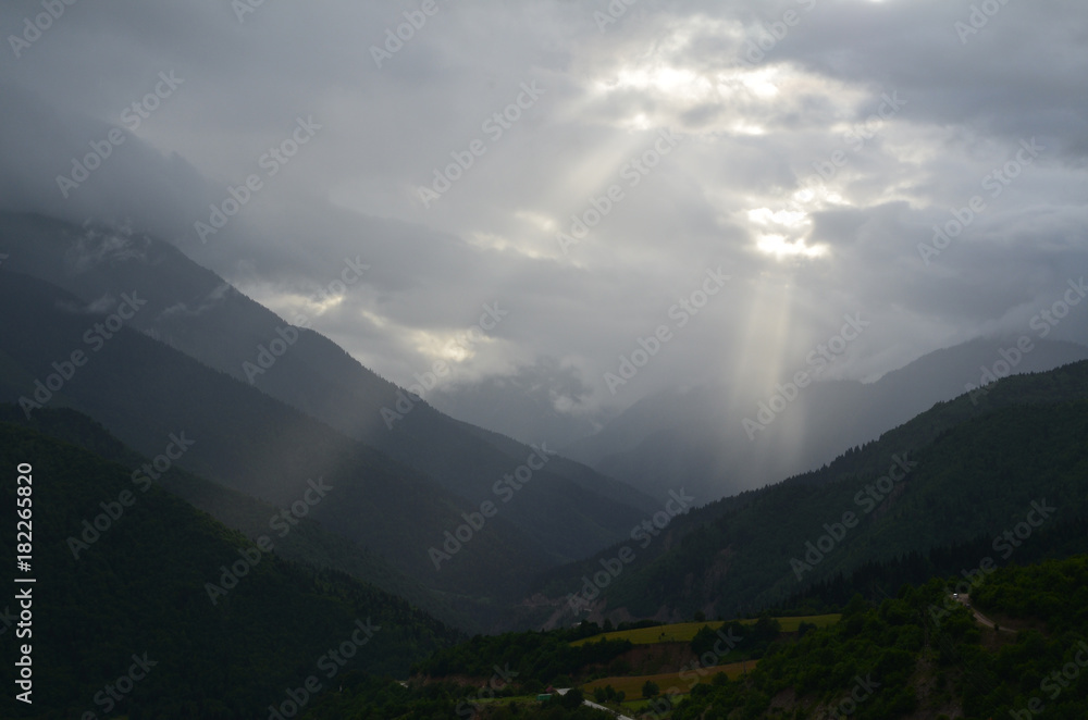 Sun breaking through the clouds on a mountain.